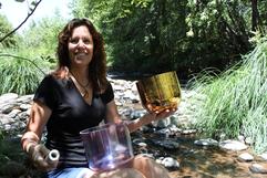 A woman sitting on the ground holding two bowls.