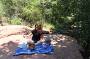Woman playing singing bowls outdoors on rock.