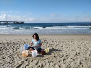 A woman sitting on the beach with some drinks