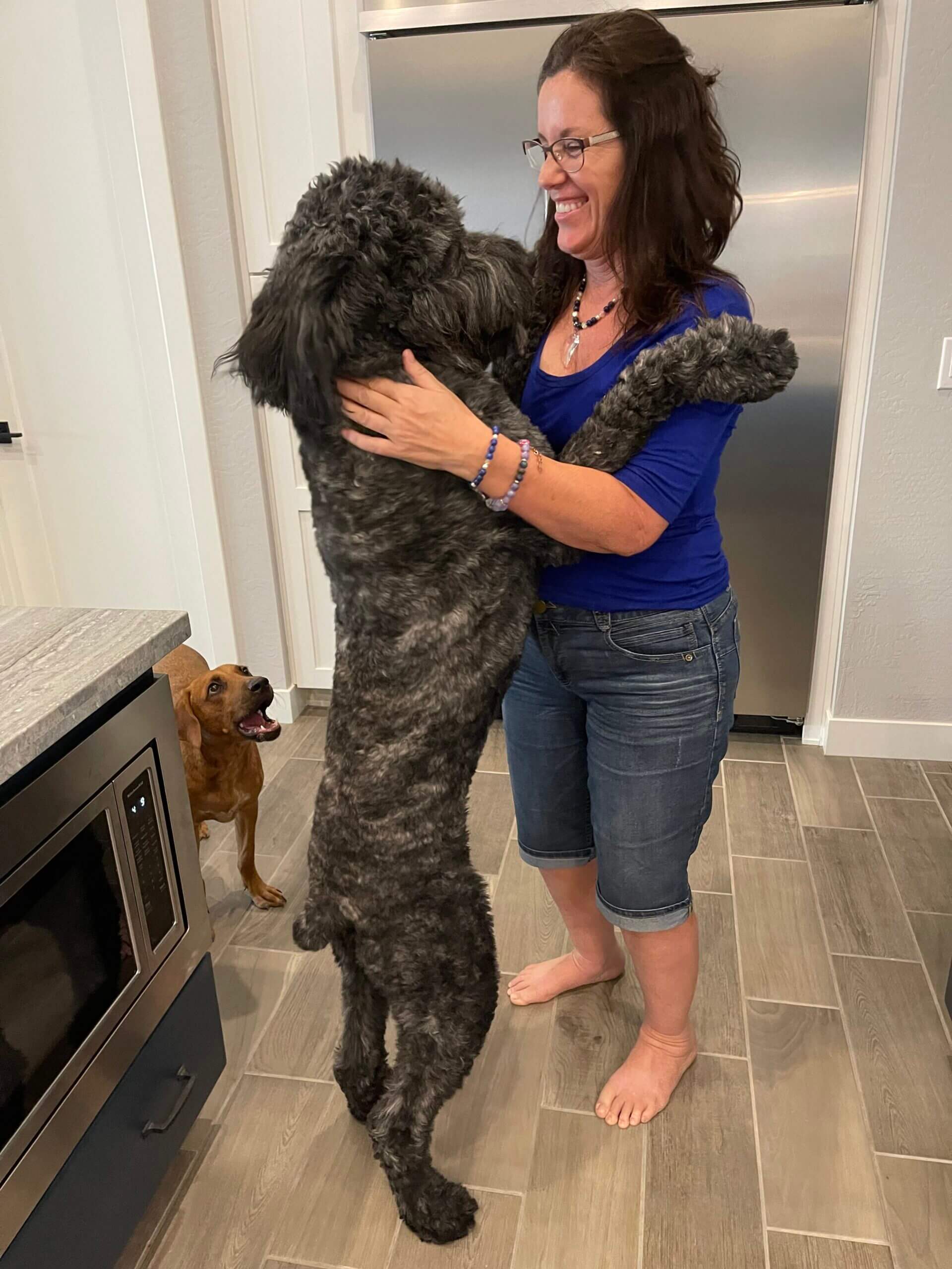 A woman and her dog are hugging each other.