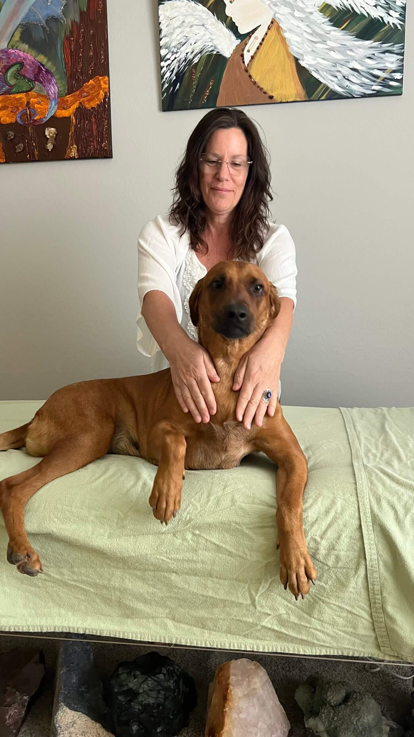 A woman is petting her dog on the bed
